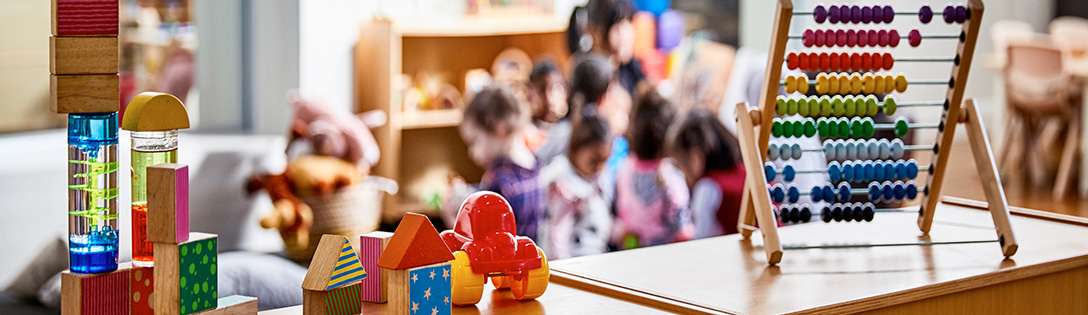 Toys on a cabinet with small children playing in the background