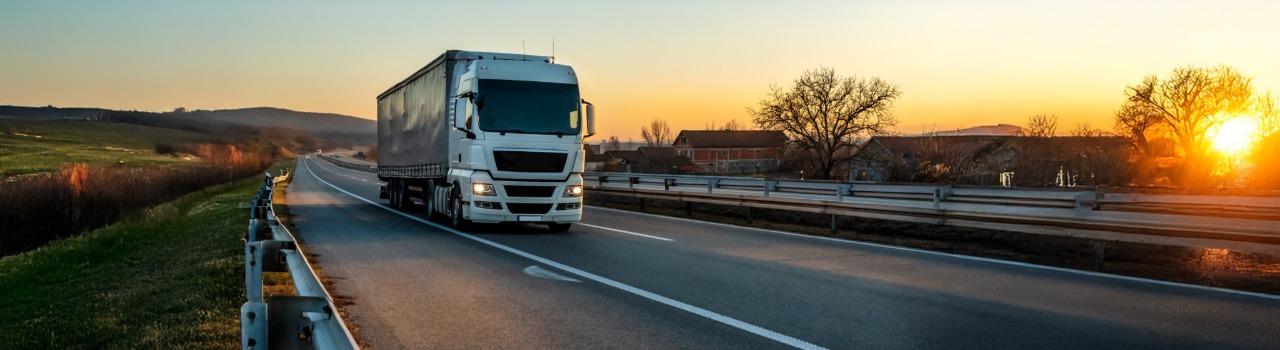 Overtaking trucks on a tarmac road in a rural landscape at sunset